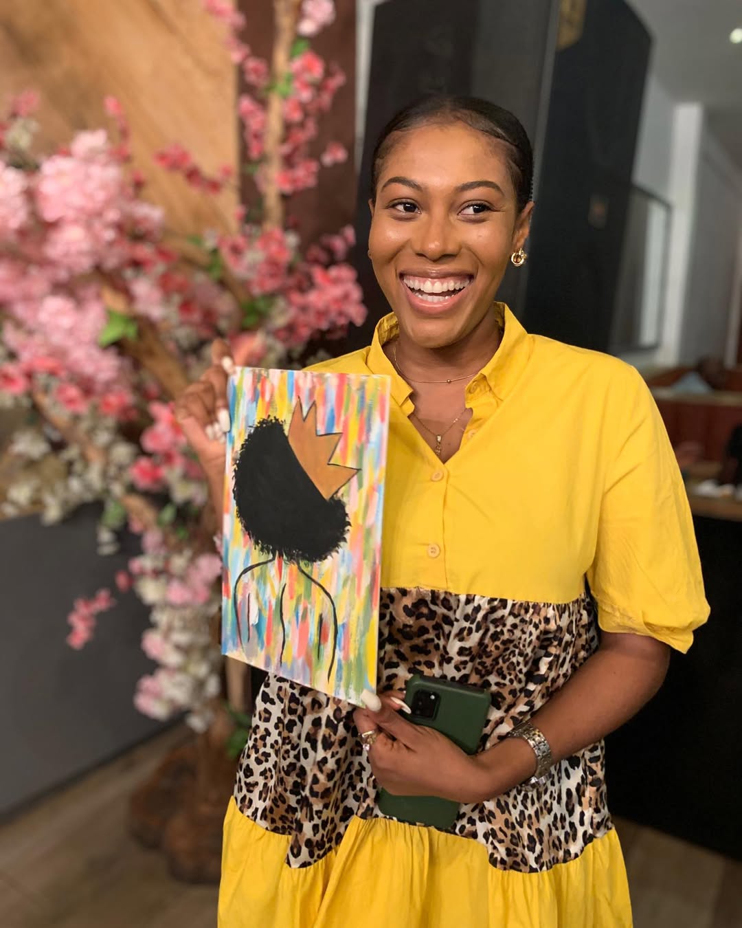 A guest with a colourful canvas in front of a styled floral backdrop at an RSS event