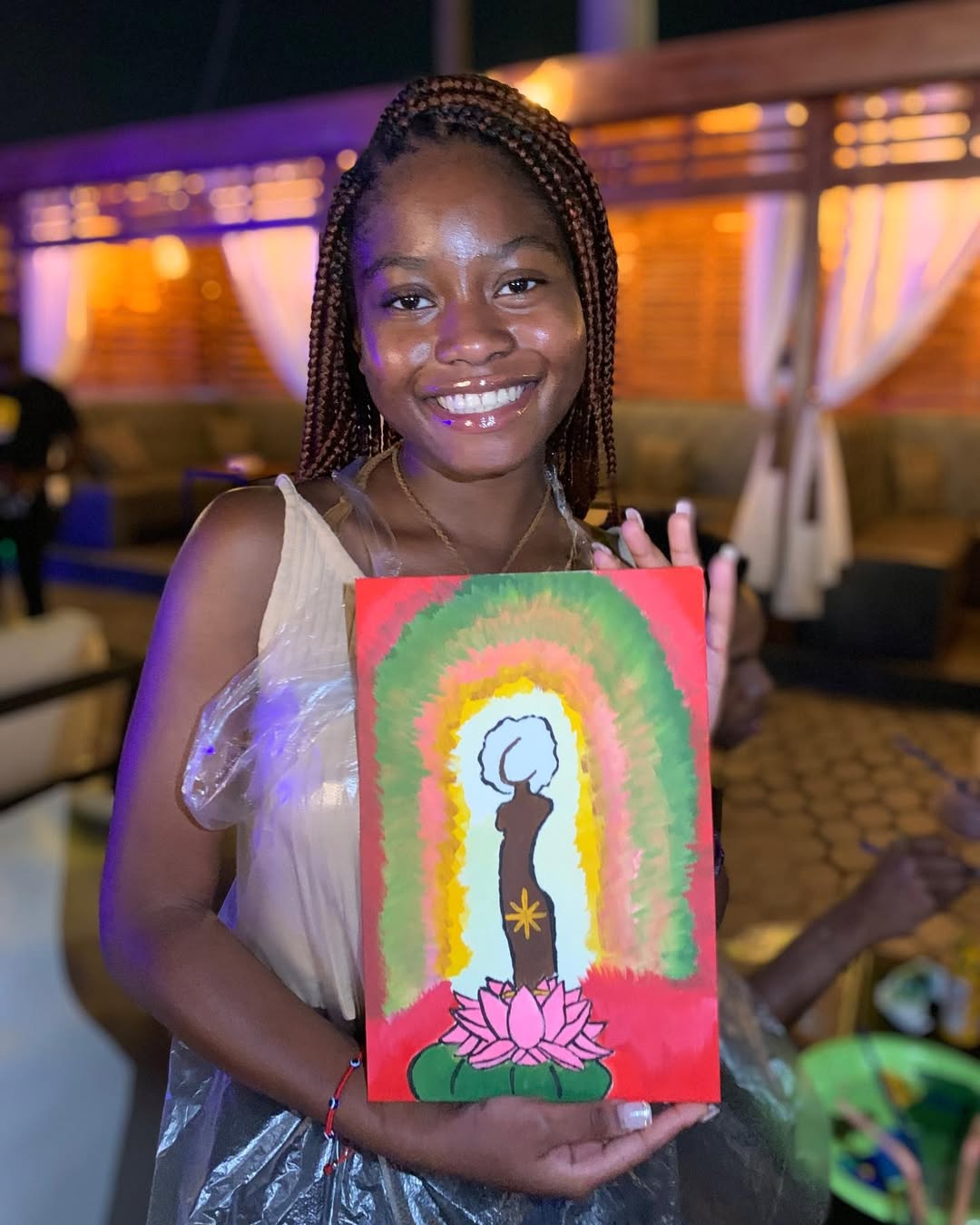 A painter holding a vivid lotus-and-figure canvas