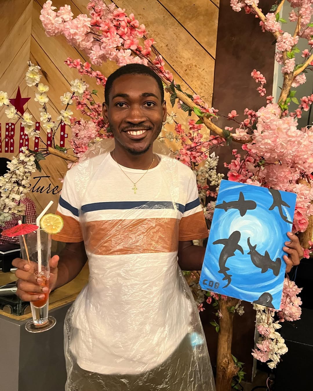 A guest with a cocktail and canvas in front of a styled cherry-blossom backdrop